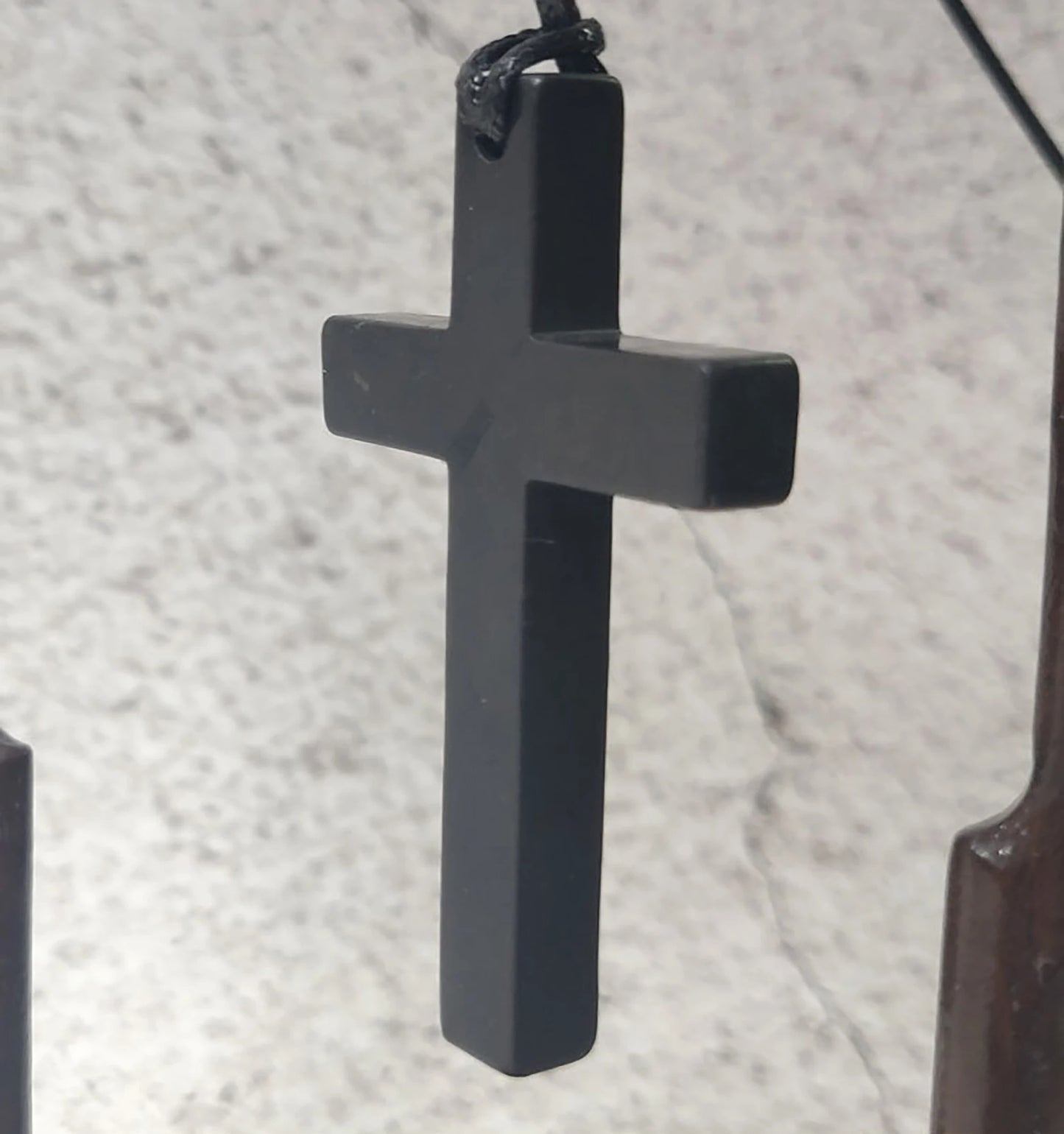 Black cross pendant on a textured gray background