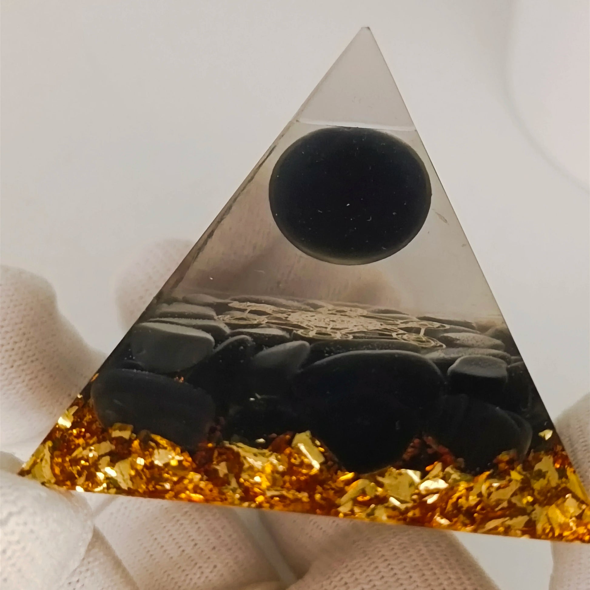 Triangular crystal with black and gold elements on a white background