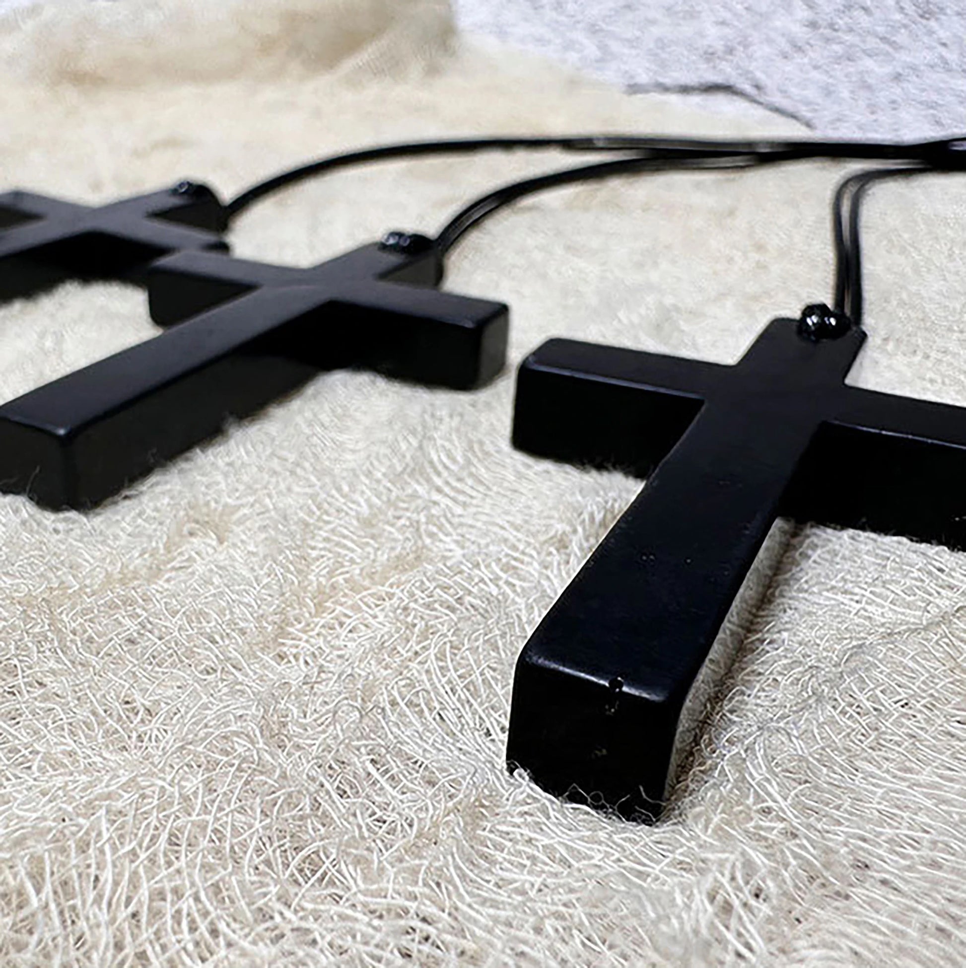Black cross-shaped pendant on a white textured surface