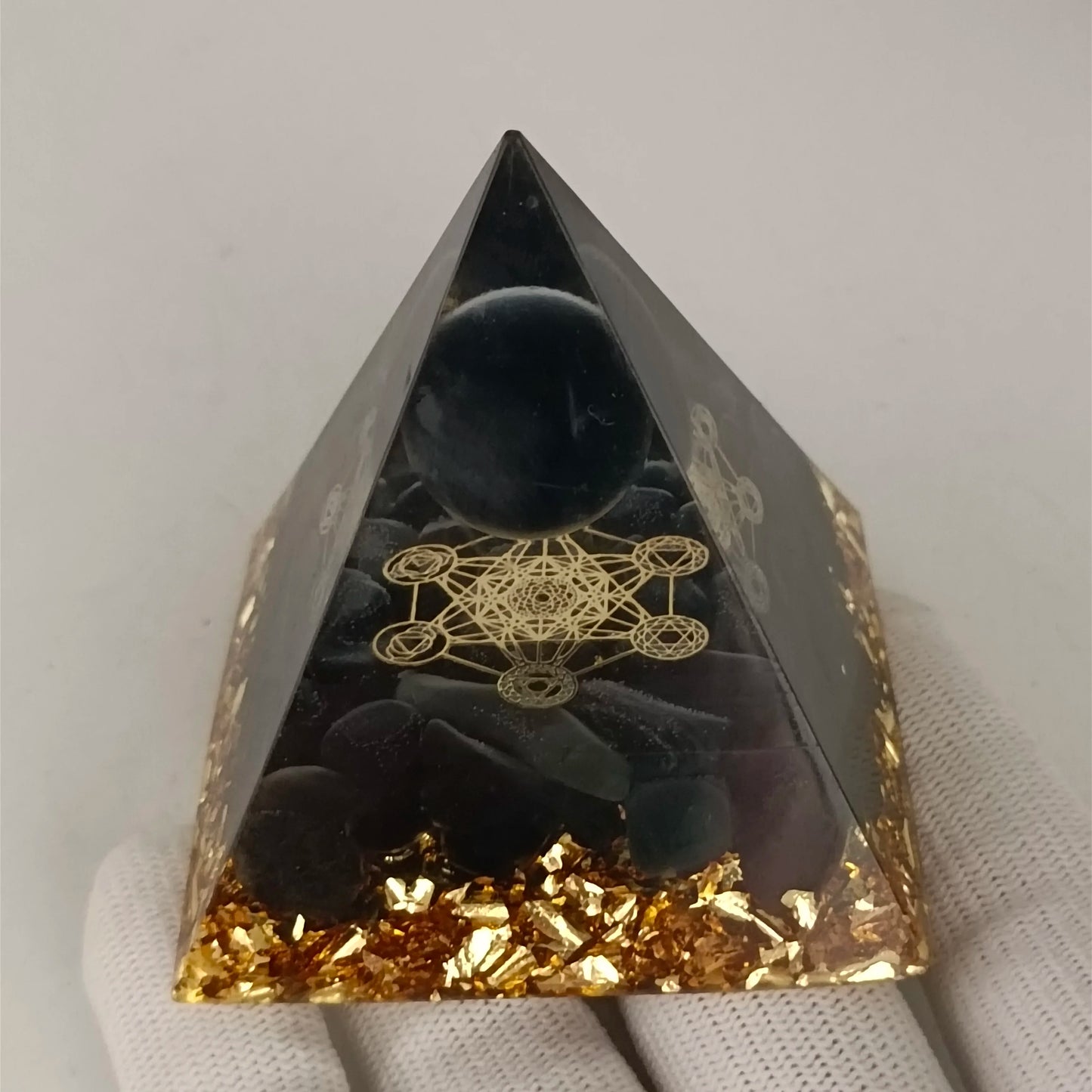 Black pyramid crystal with gold leaf and geometric design on a white background