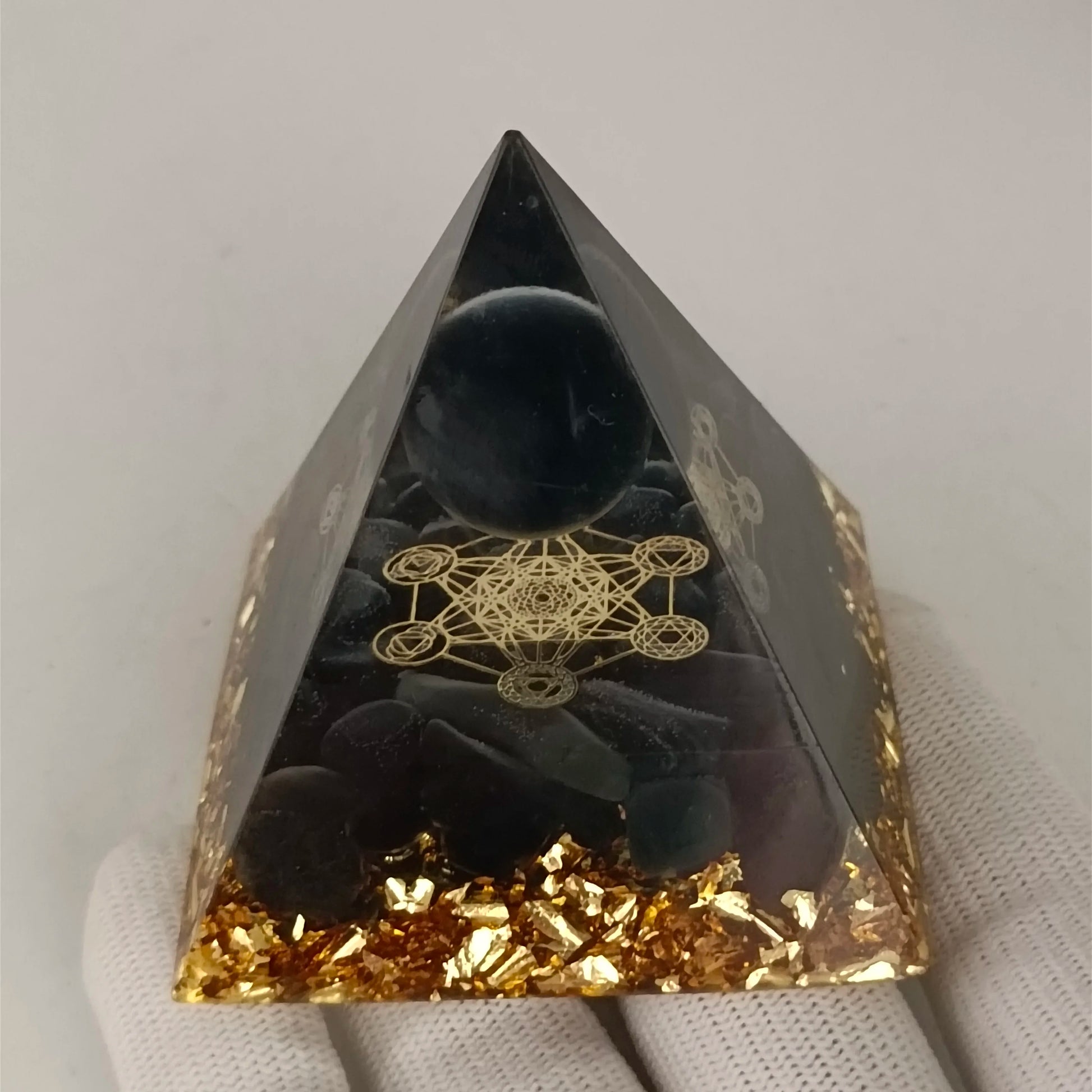 Black pyramid crystal with gold leaf and geometric design on a white background