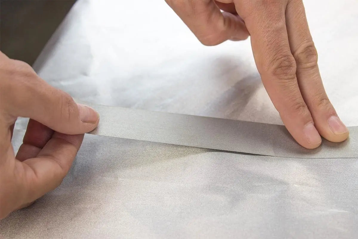 Person applying a strip of tape on a white surface