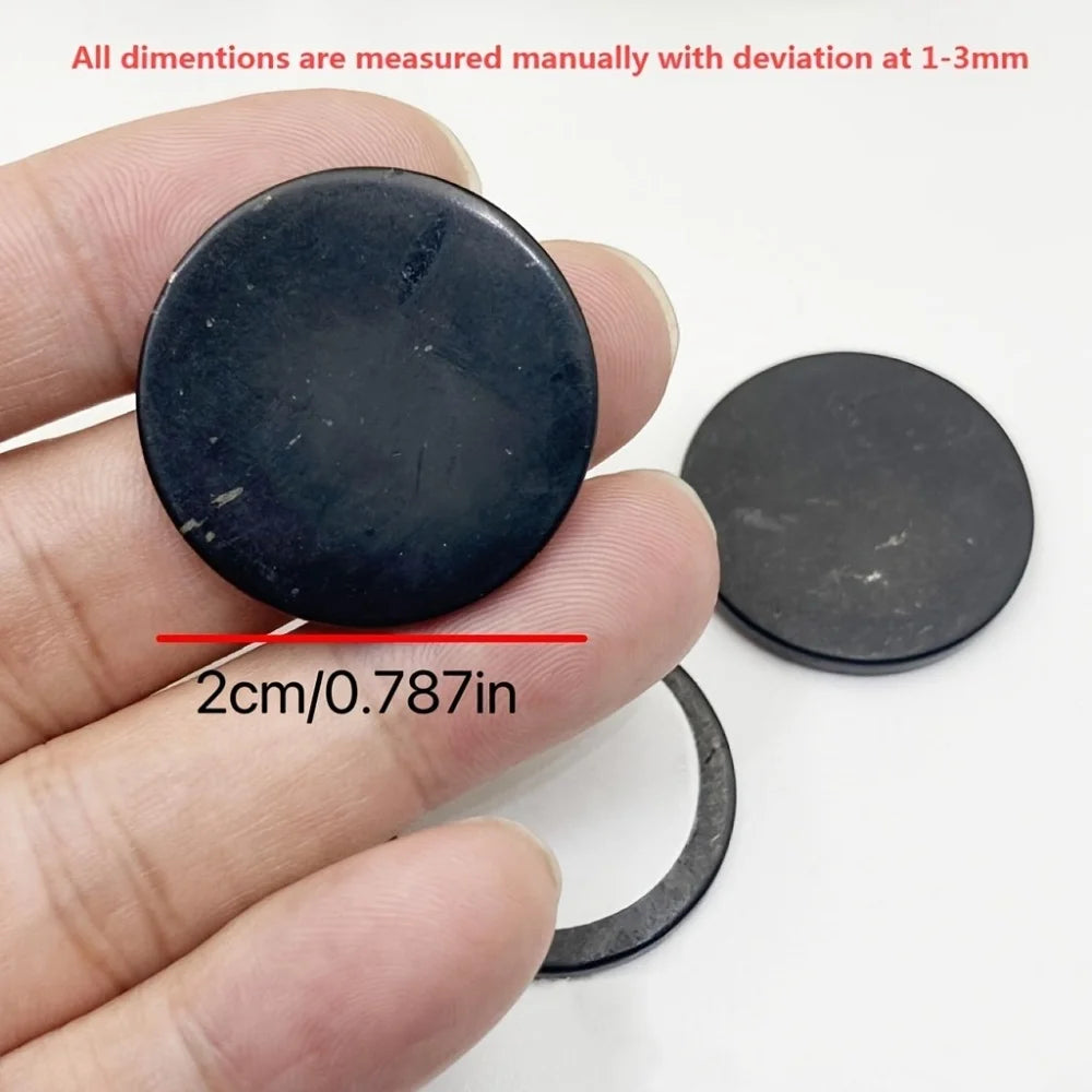 Black circular object held between fingers with measurement text overlay