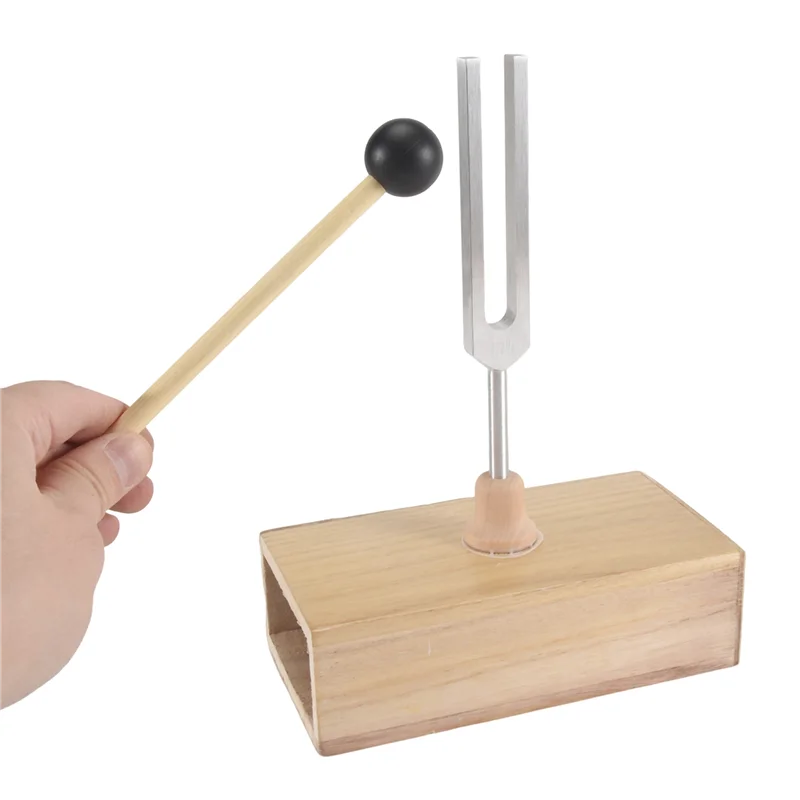 Tuning fork with wooden base and hand holding a mallet on a white background