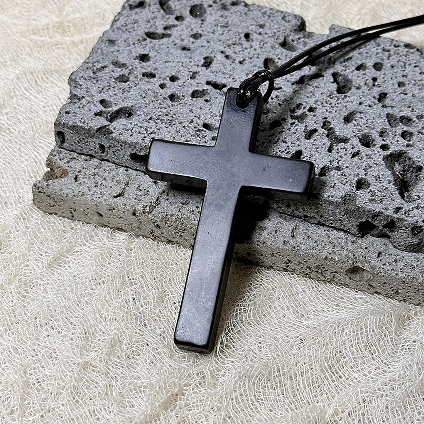 Black cross pendant on a stone surface