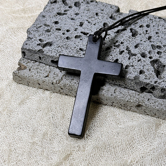 Black cross pendant on a stone surface